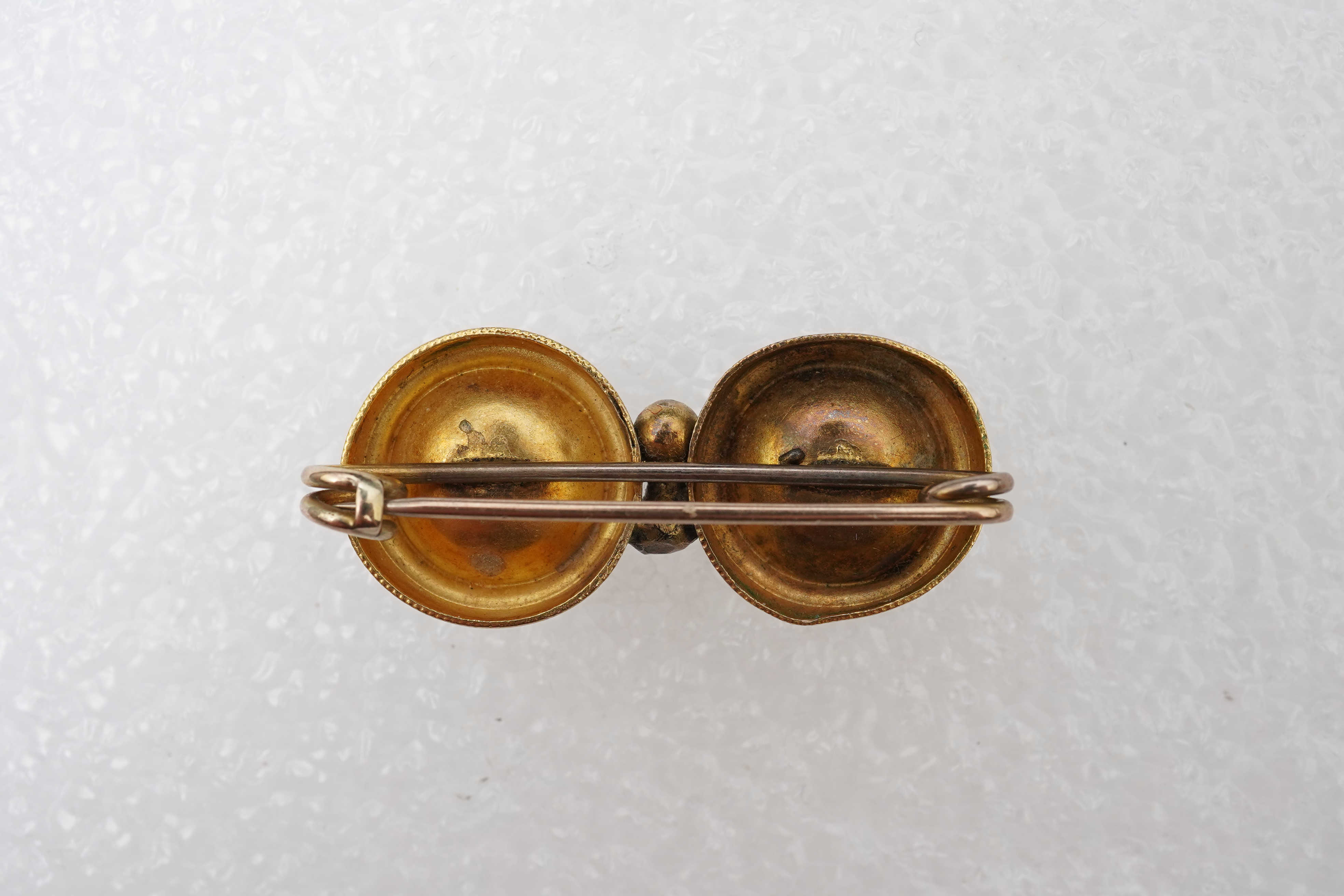 A Victorian ruby and gold double target brooch, late 19th century and later, composed of two roundels set with circular-cut garnets, with wirework details, length 3.7cm, gross weight approximately 3.5 grams